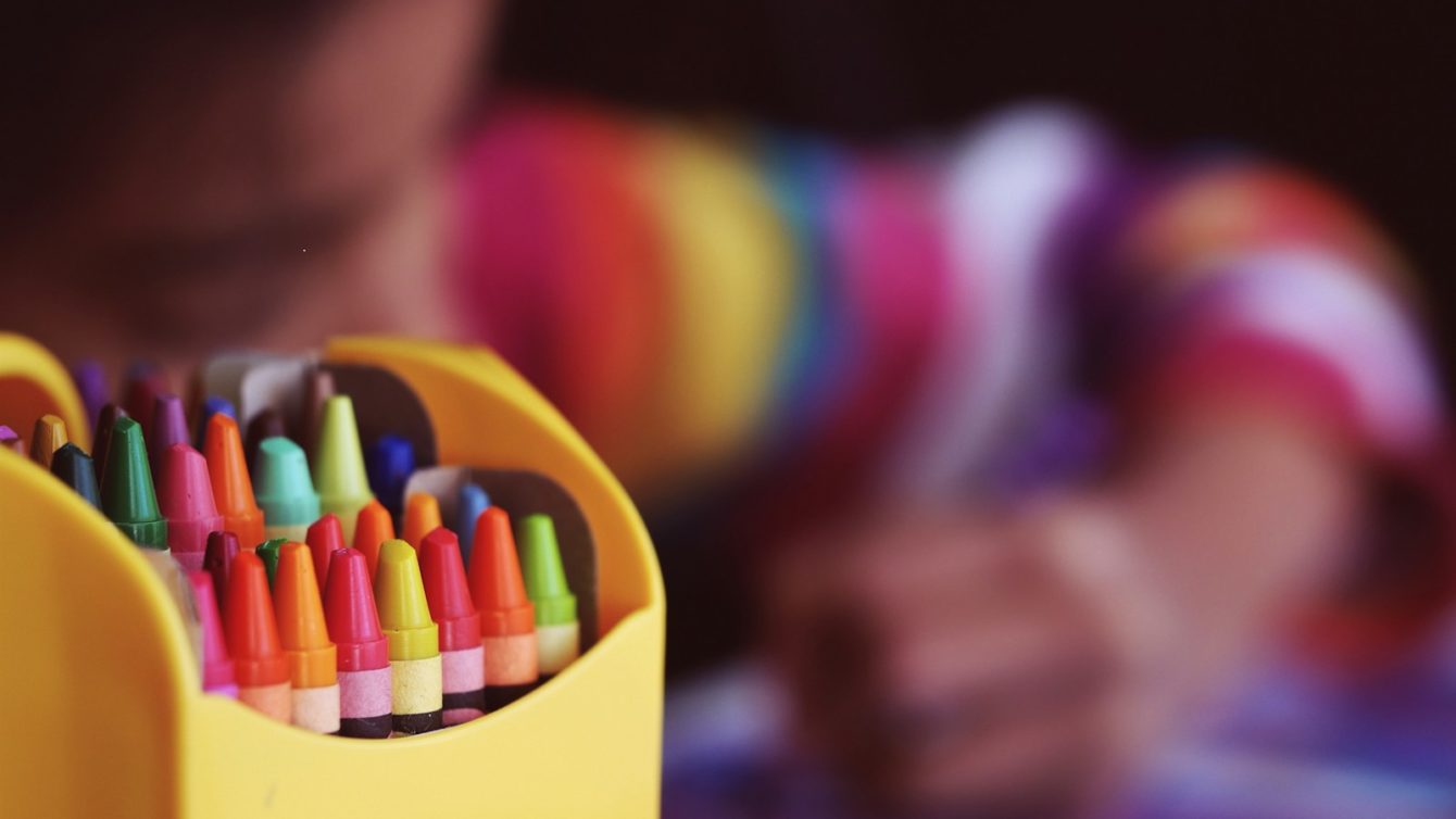 selective focal photo of crayons in yellow box