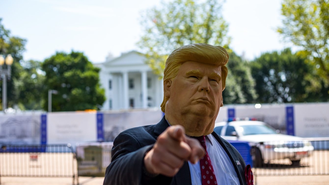 man wearing Donald Trump mask standing in front of White House